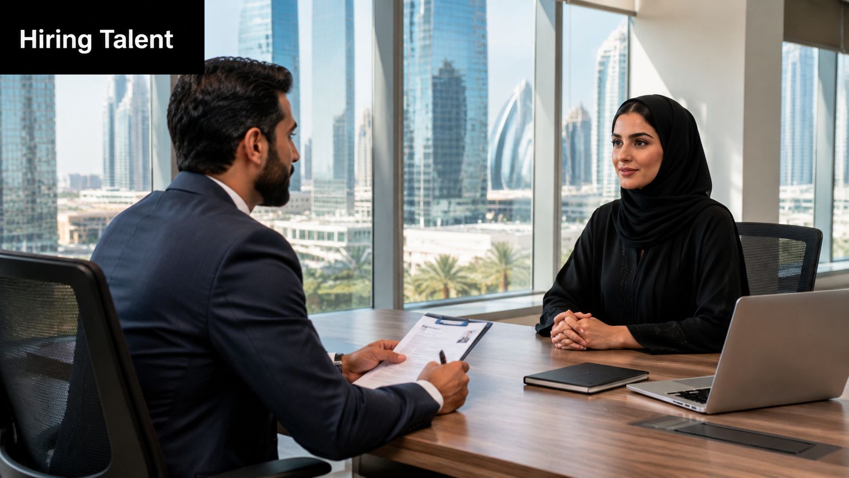 A professional job interview taking place in a modern Dubai office with a city skyline view.